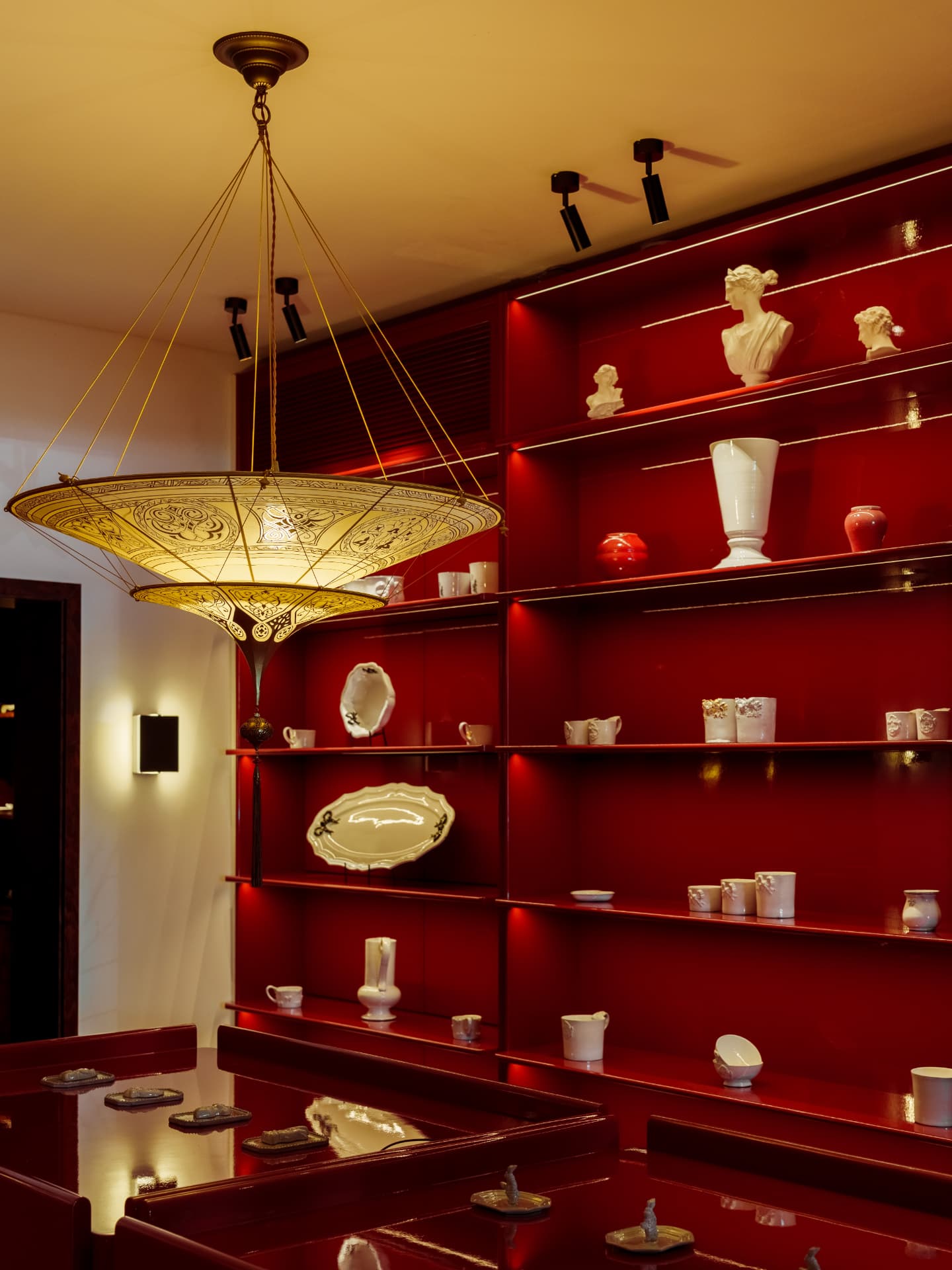The brass chandelier and red lacquer shelves with white porcelain inside the M E T store